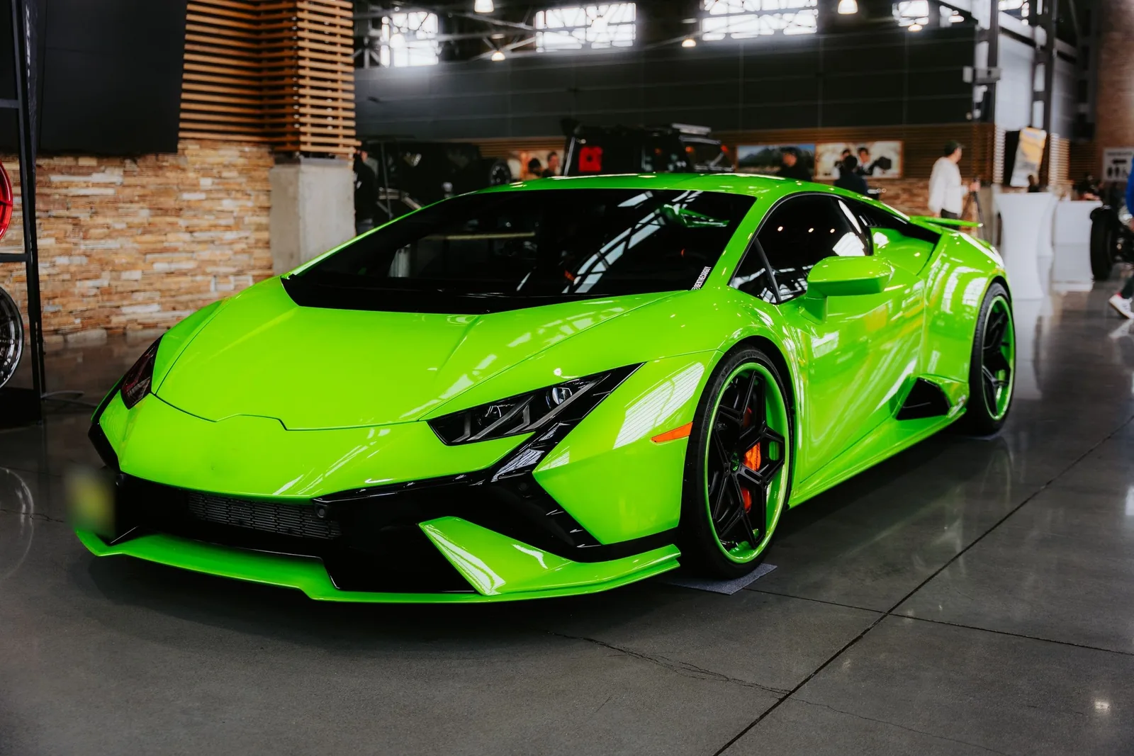 A green sports car on a showroom floor, light running along the paint