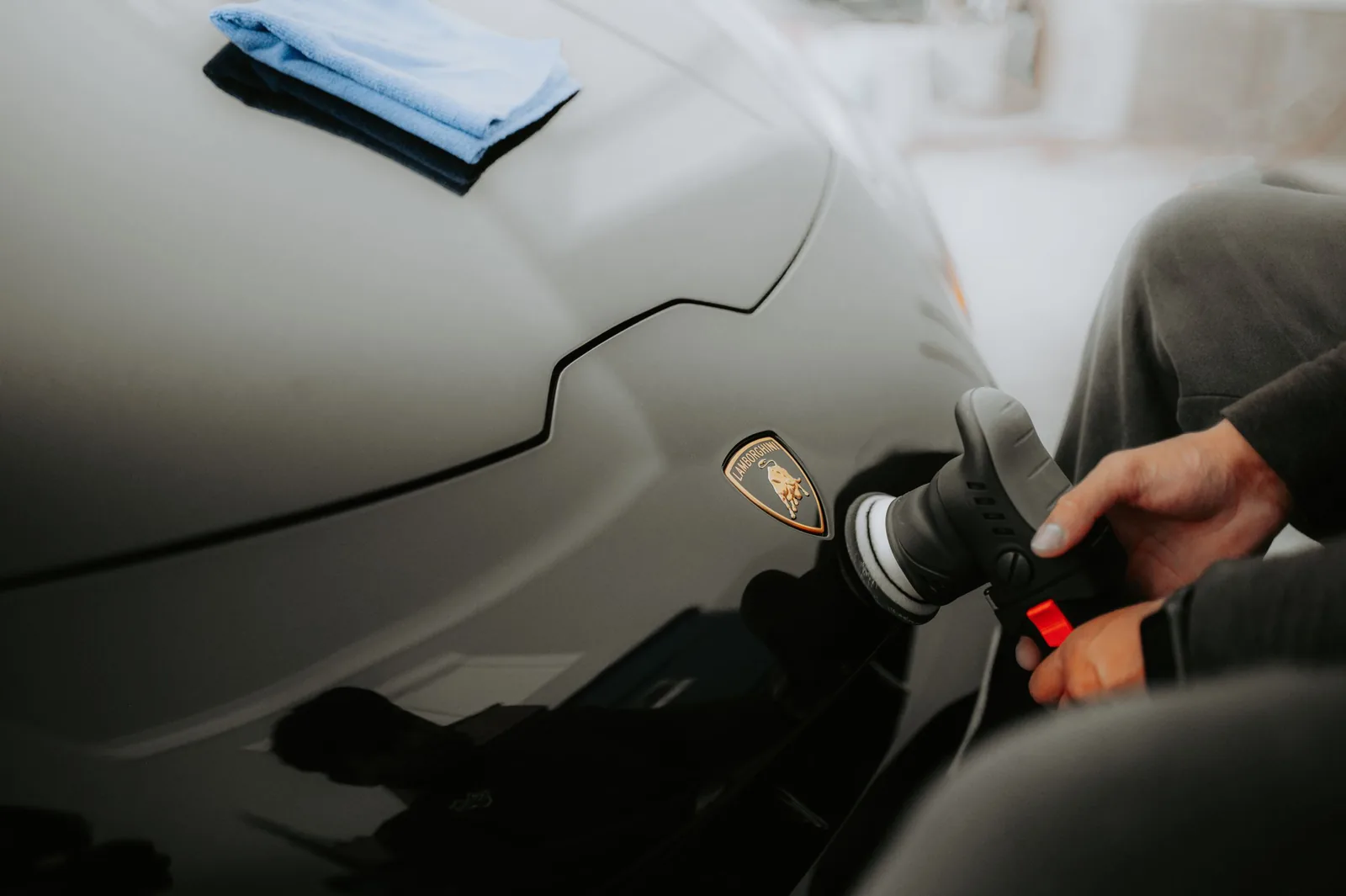 A polisher working on the bonnet of a supercar