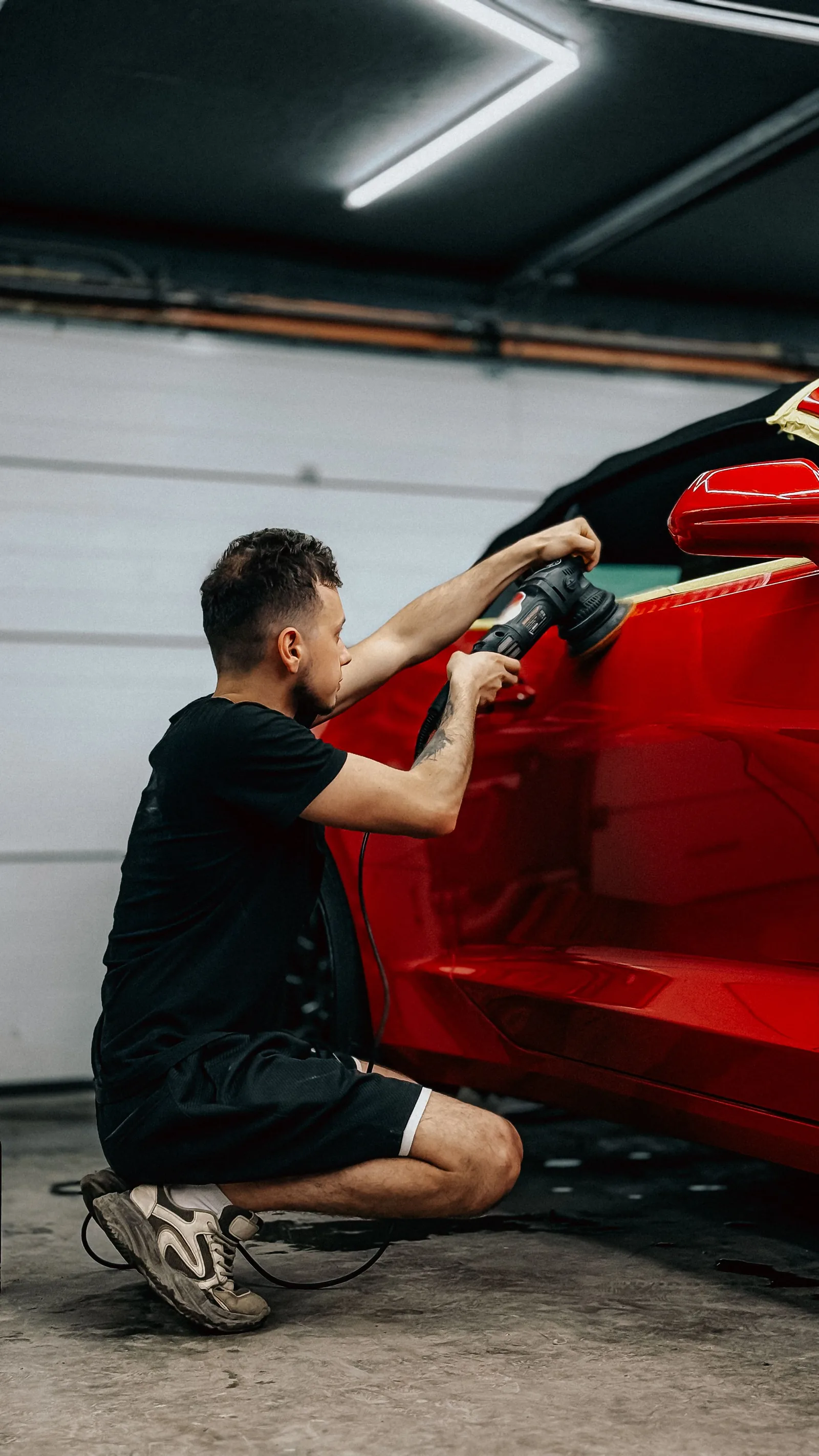 A detailer polishing the door of a red sports car