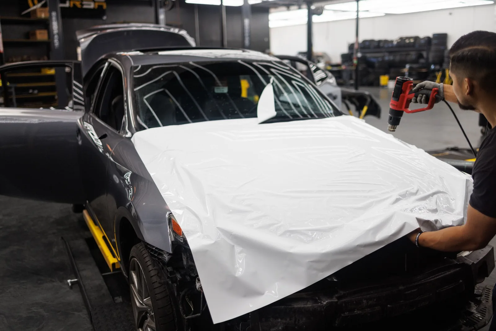 Grey sports coupe being wrapped in white film