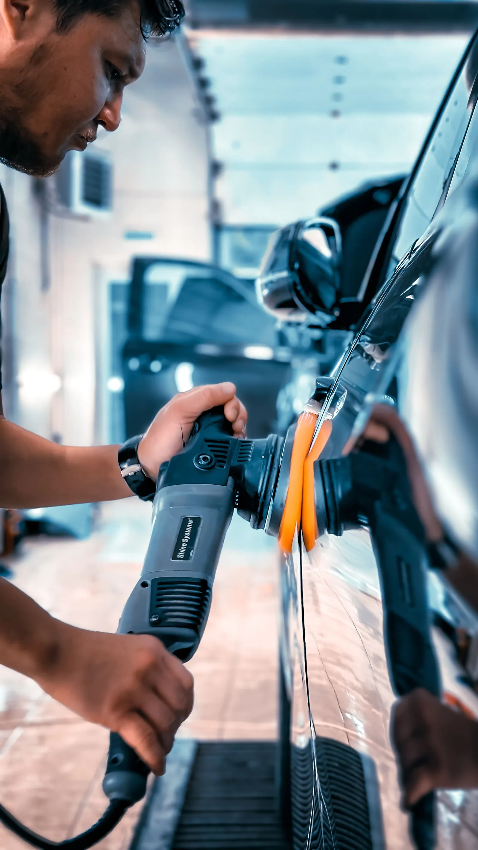 A detailer working the paint with an electric polisher