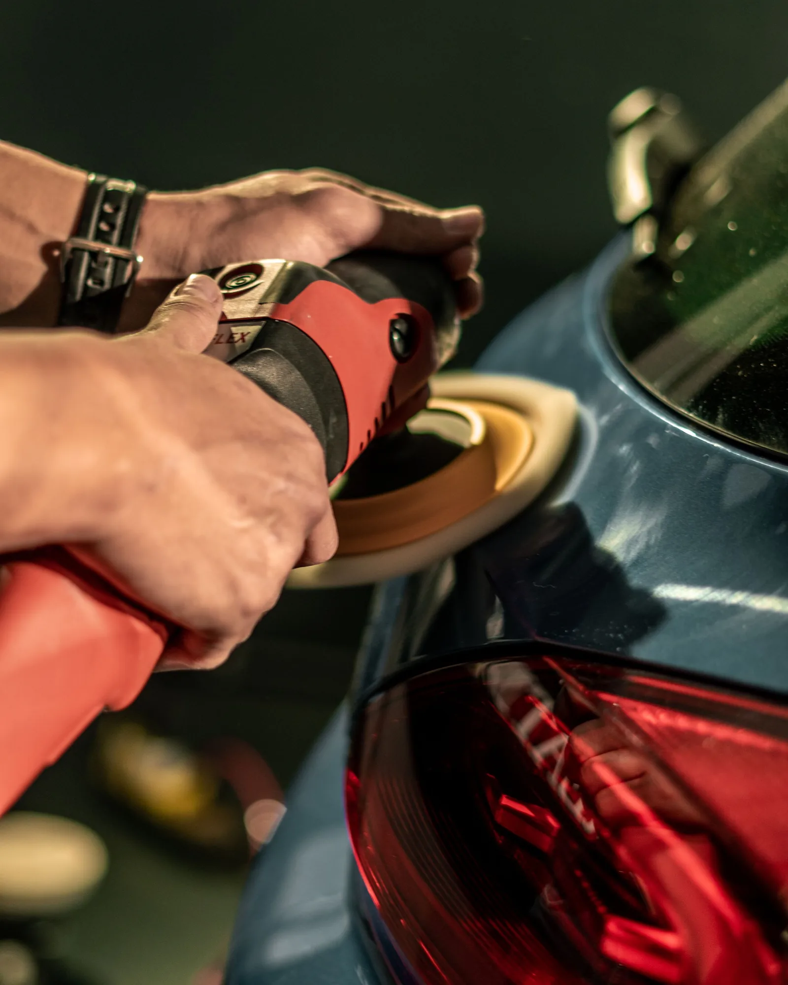 A polisher on the wing of a dark car